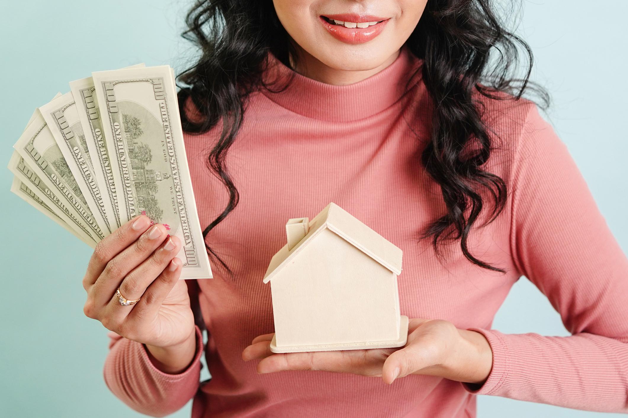 A lady holding money and mini house